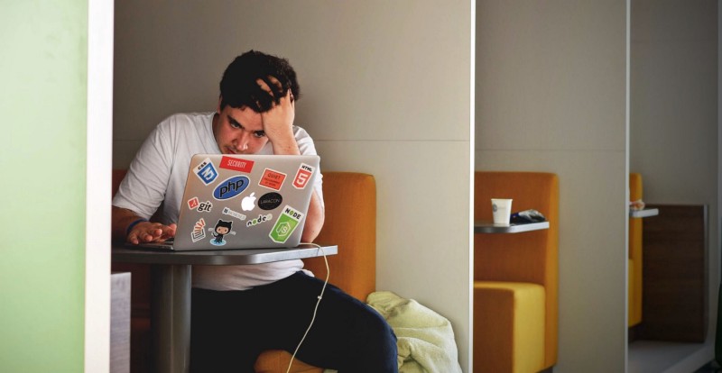 Man sitting at his laptop, clearly frustrated with what is on the screen